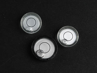 Three glass circular bubble level vials. One is painted with black color.